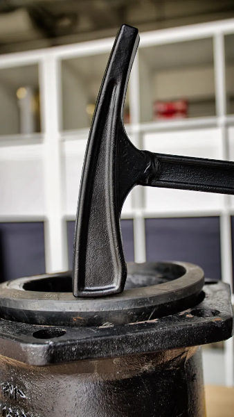 Close-up of a black metal valve handle with a blurred indoor background